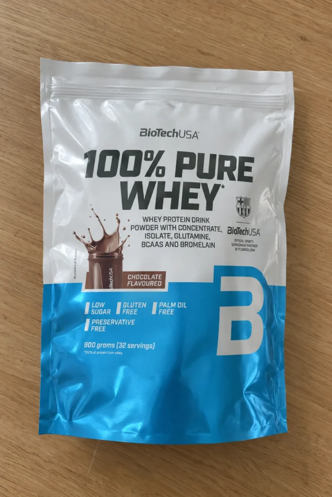 Sachet de 100% Pure Whey BioTechUSA goût chocolat 900 g posé à plat sur une table en bois